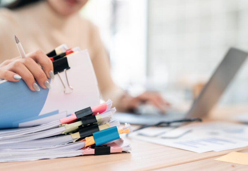 Businesswoman hands working in Stacks of paper files for searching and checking unfinished document