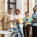 interracial business people looking at camera in office, coworking, folders, gadgets, generation z