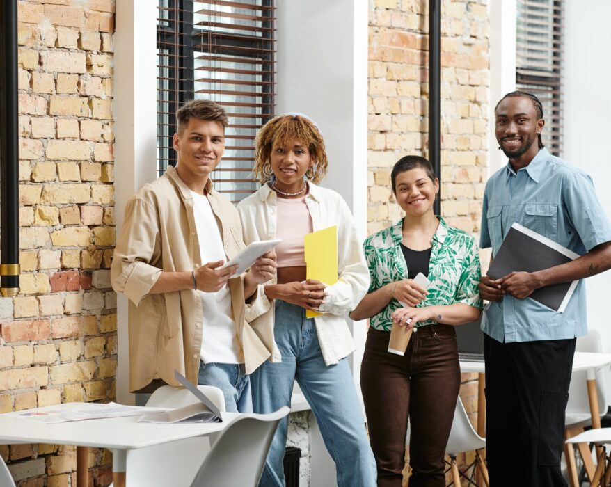 interracial business people looking at camera in office, coworking, folders, gadgets, generation z
