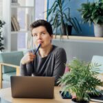 Middle aged minded pensive employee business woman in casual clothes holds a pen, works at office