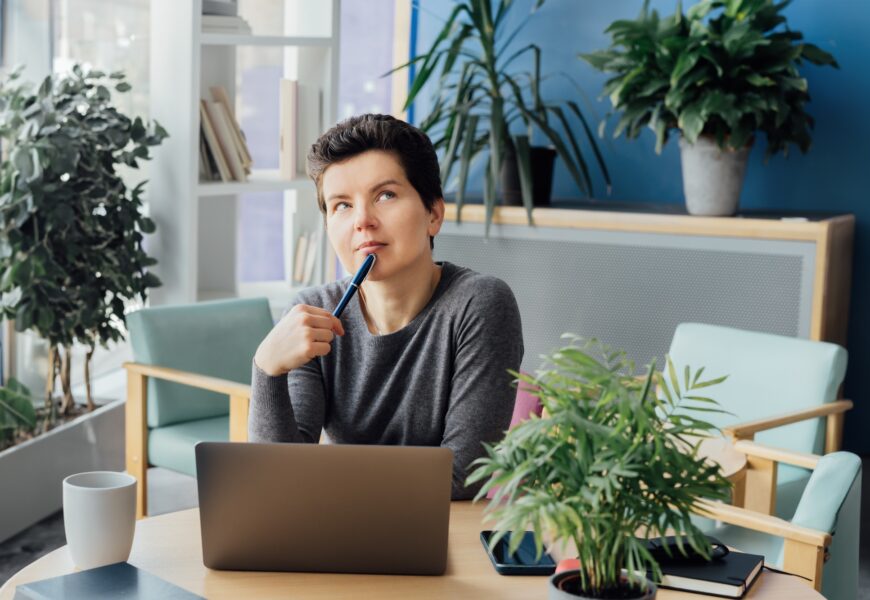 Middle aged minded pensive employee business woman in casual clothes holds a pen, works at office