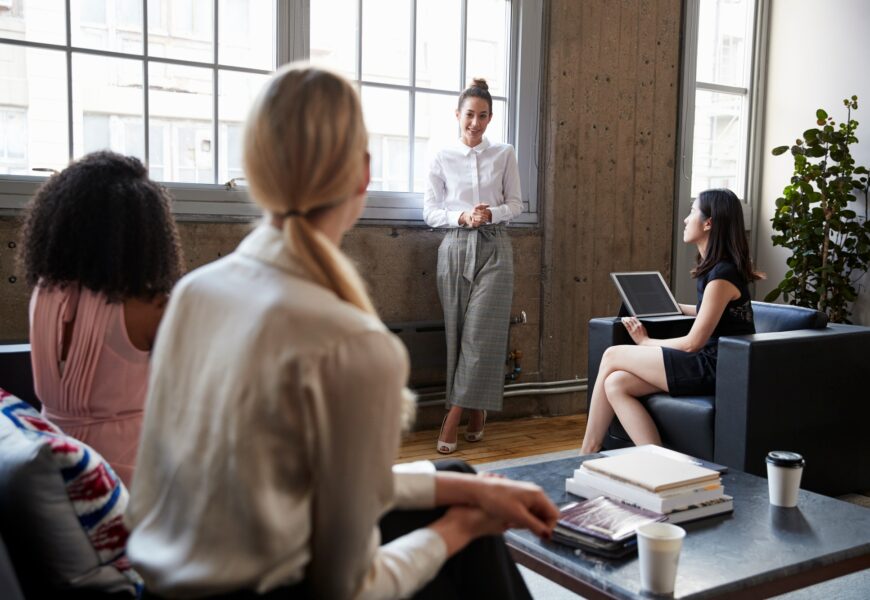 Standing female manager talking to team at casual meeting